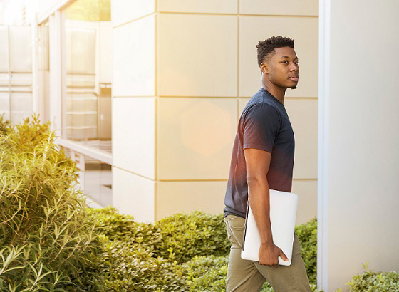 Student walking to class with laptop