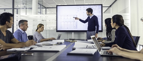 Employee presenting to a group of multigenerational employees in a conference room