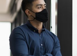 Man with a mask looking out a window