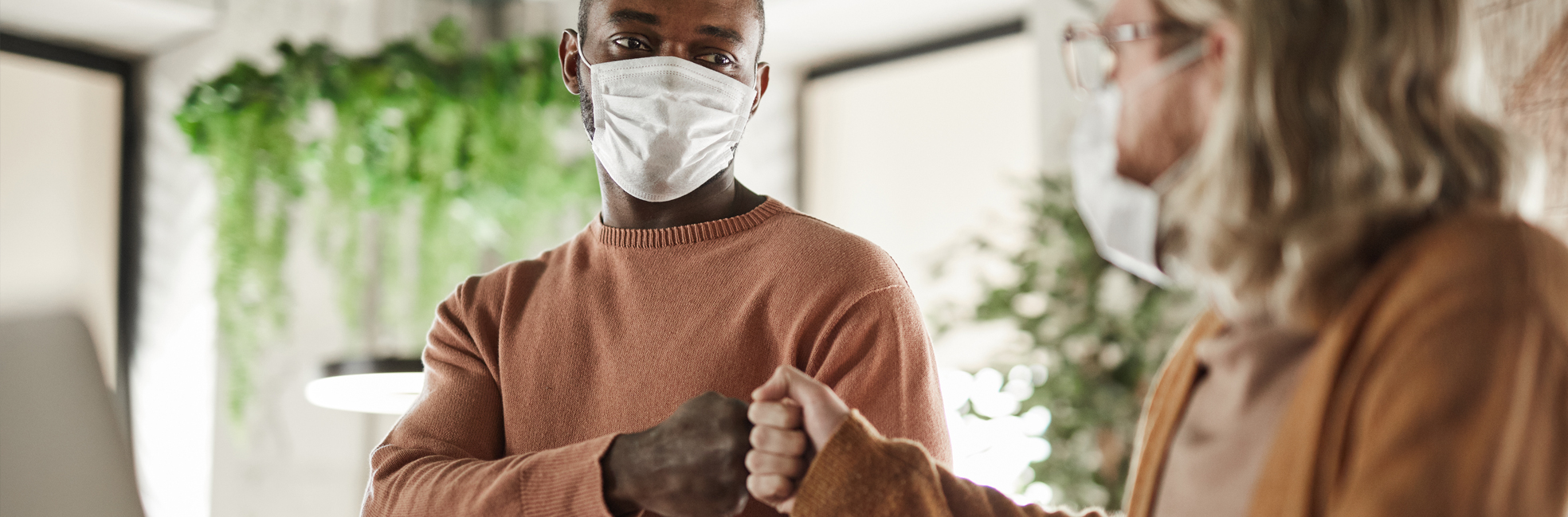 Individuals wearing face masks and fist bumping