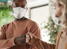 Individuals wearing face masks and fist bumping